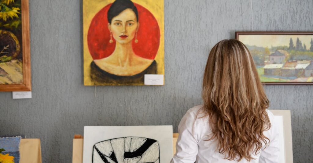 A woman views paintings in an art gallery, appreciating various art styles on display.